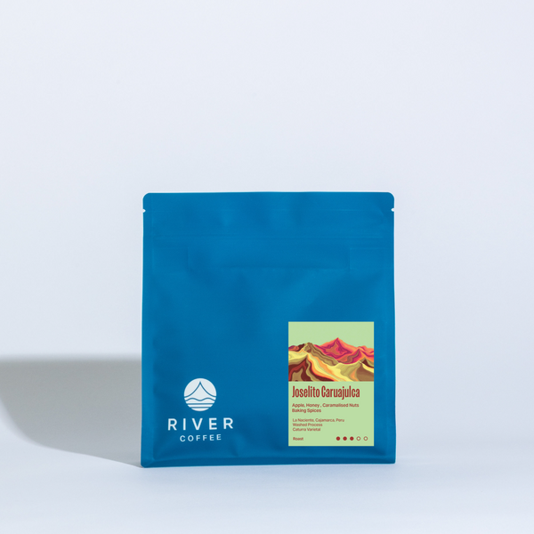 Blue coffee package with 'River Coffee' branding on a light gray background