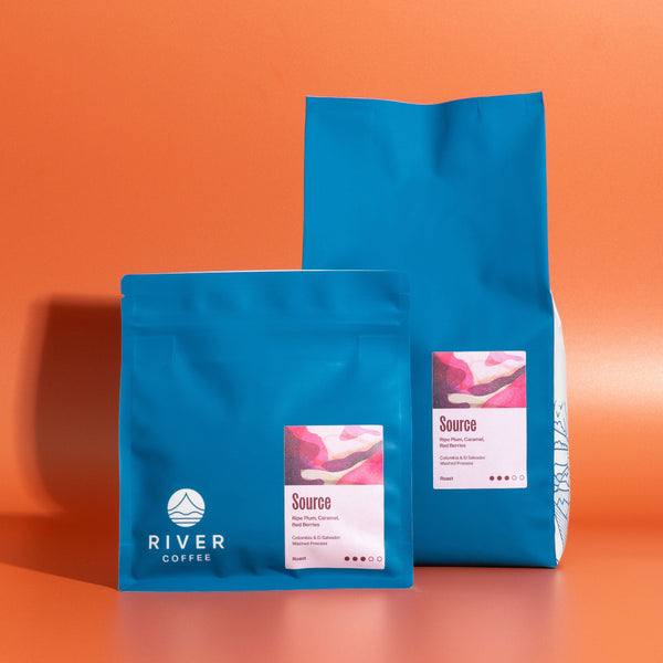 Two blue coffee bags with 'River Coffee' branding on an orange background