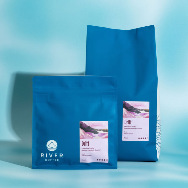 Two blue coffee bags with 'River Coffee' branding on a light blue background