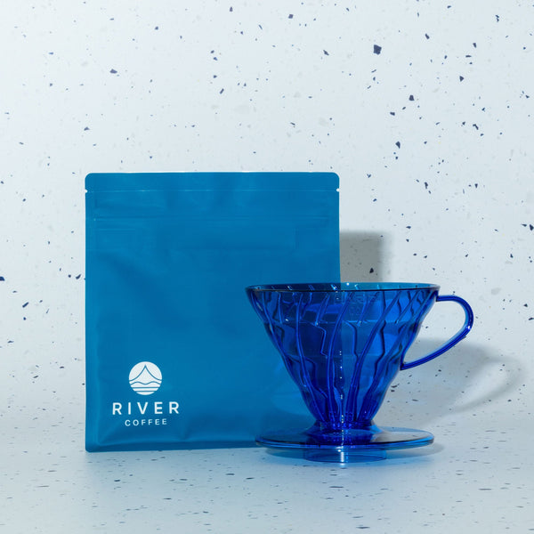 Blue coffee filter and coffee package on a speckled white background