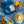 Blue coffee bag with 'River Coffee' branding, a cup of coffee with latte art, and sliced oranges on a blue checkered tablecloth.