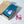 Open cardboard box with a blue coffee bag labeled 'River Coffee' on a speckled surface.