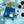 A blue bag of River Coffee Roasters coffee is displayed in a styled flat-lay on a light blue surface, surrounded by citrus fruits, berries, and cups of freshly brewed coffee, with a hand pouring coffee in the top right corner.
